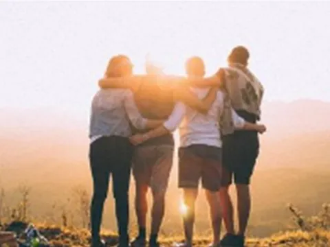 Gruppe Freunde umarmt bei Sonnenuntergang.