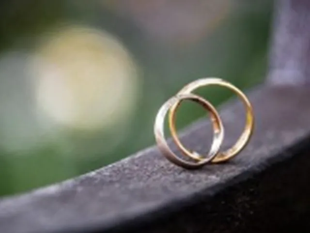 Zwei goldene Eheringe, Einheit symbolisierend.
